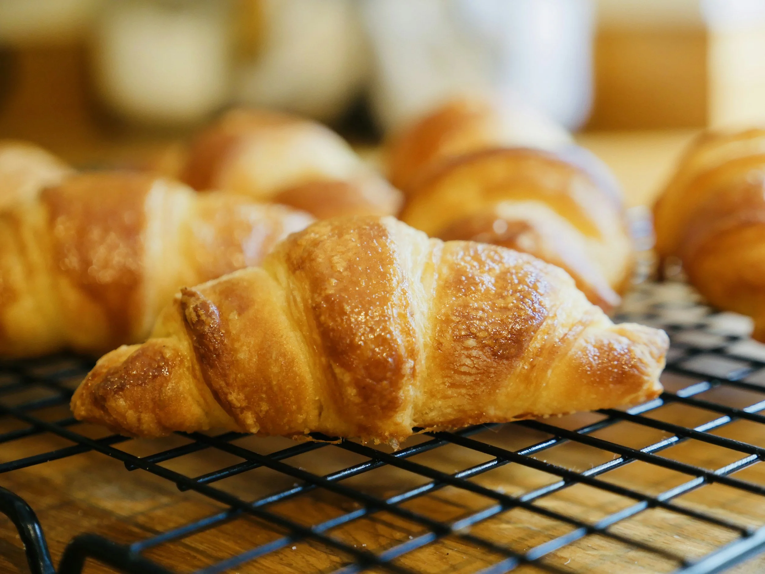 Freshly baked croissants cooling on a wire rack, golden brown and flaky.