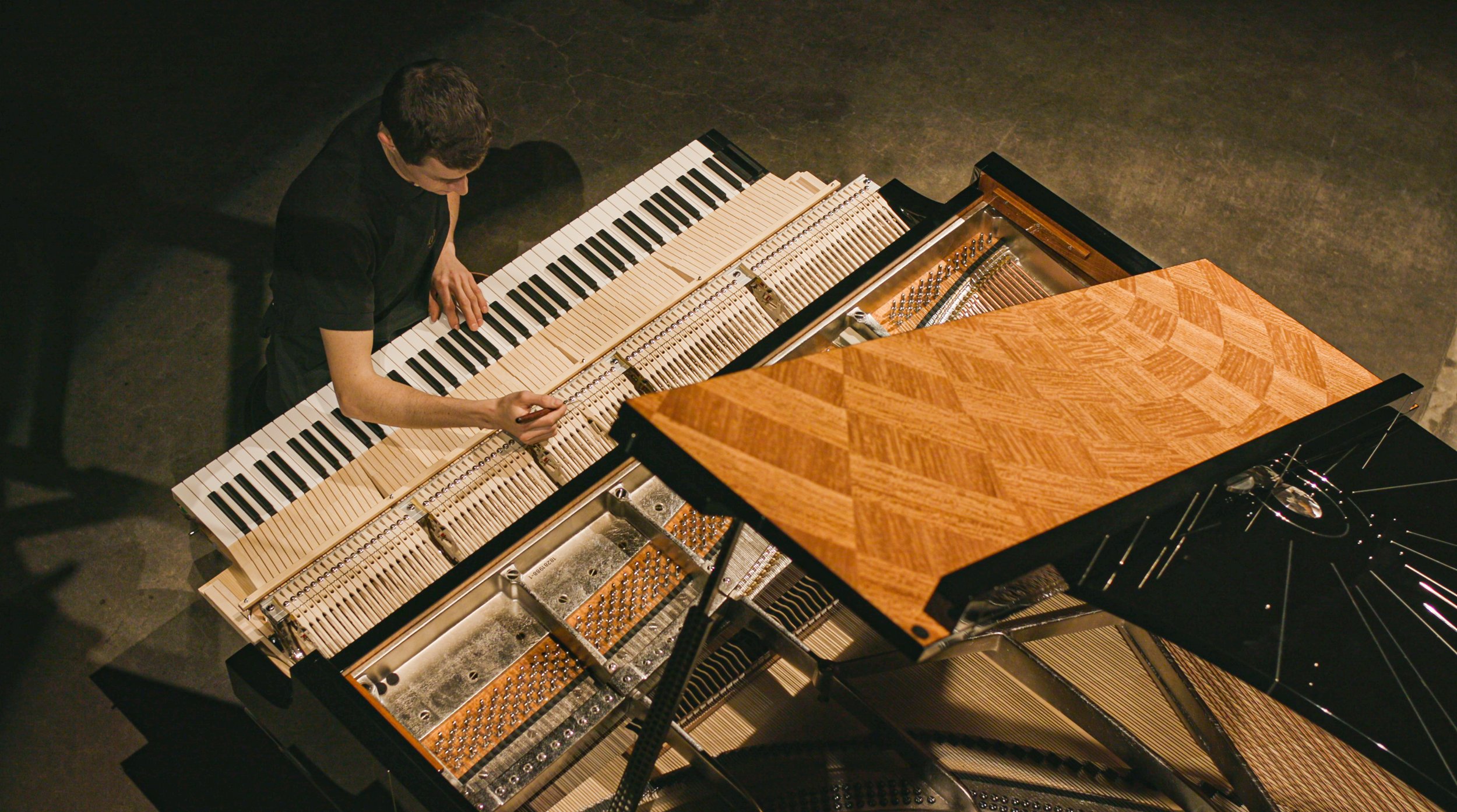 A person playing a grand piano with the lid open, revealing the strings and hammers inside.