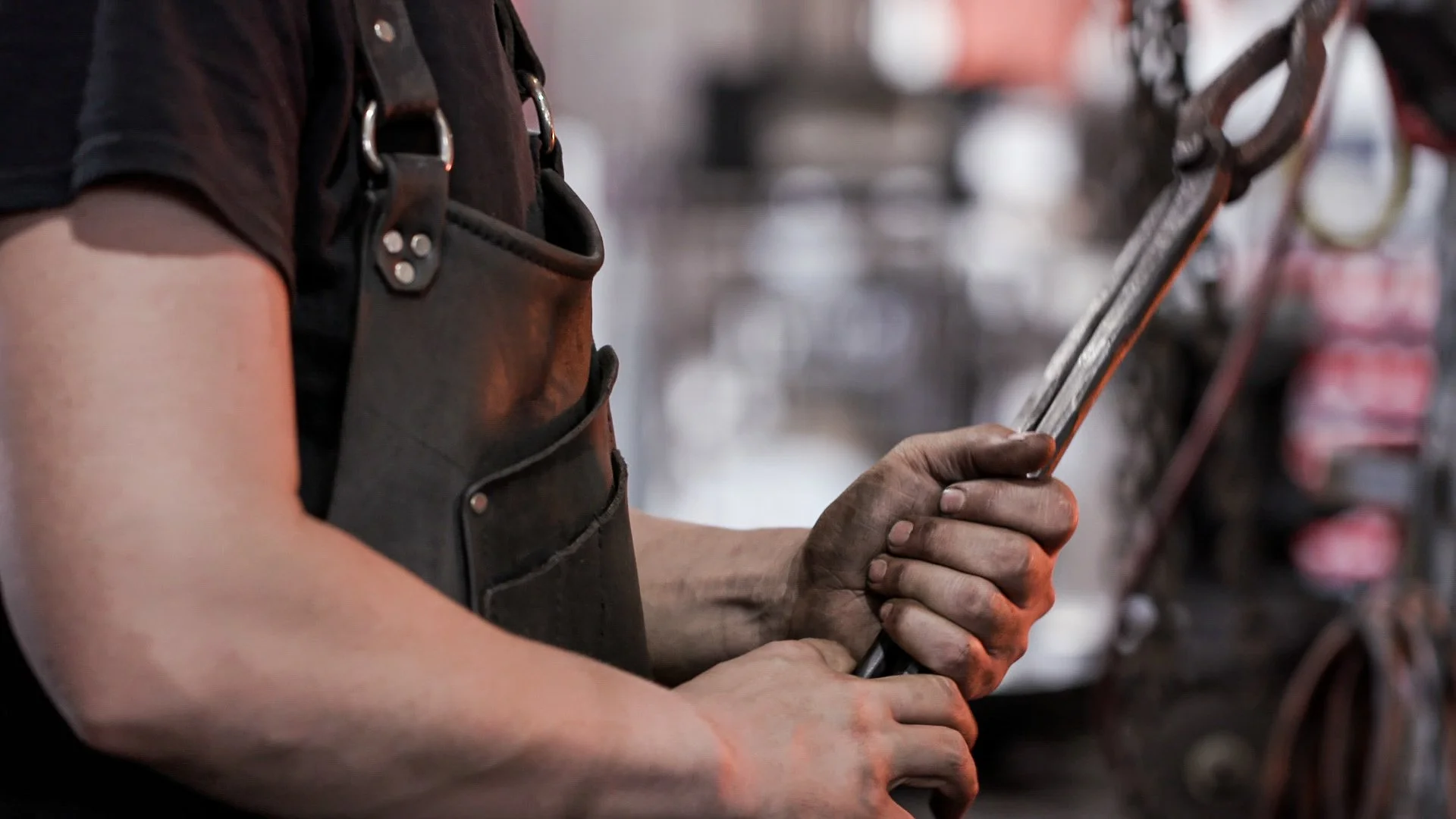 A worker with dirty hands using a wrench in a workshop.