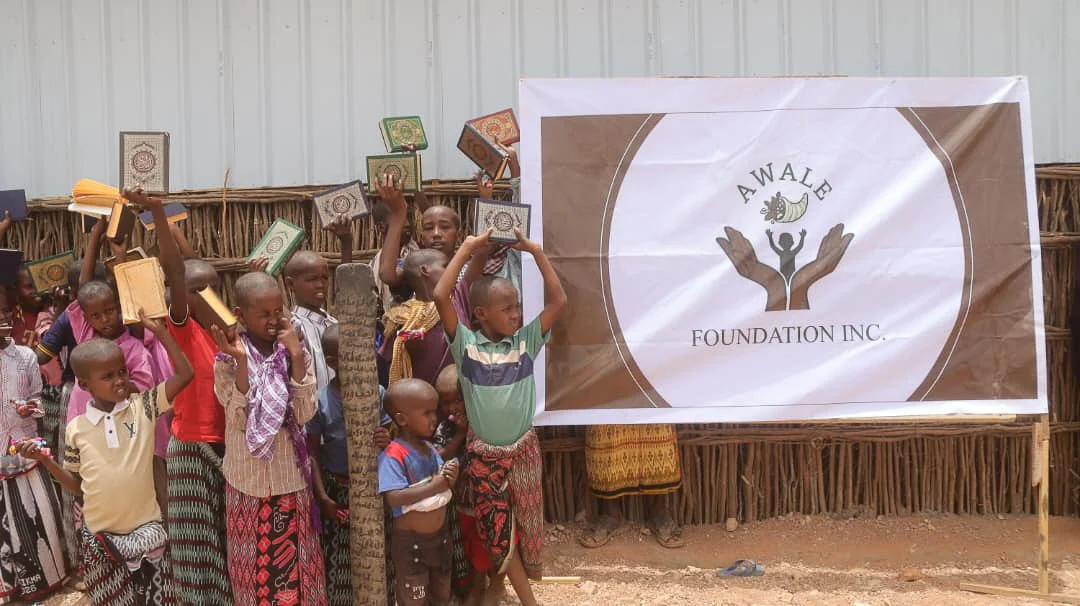 Children showcasing their new books in front of the new school built by the Awale Foundation