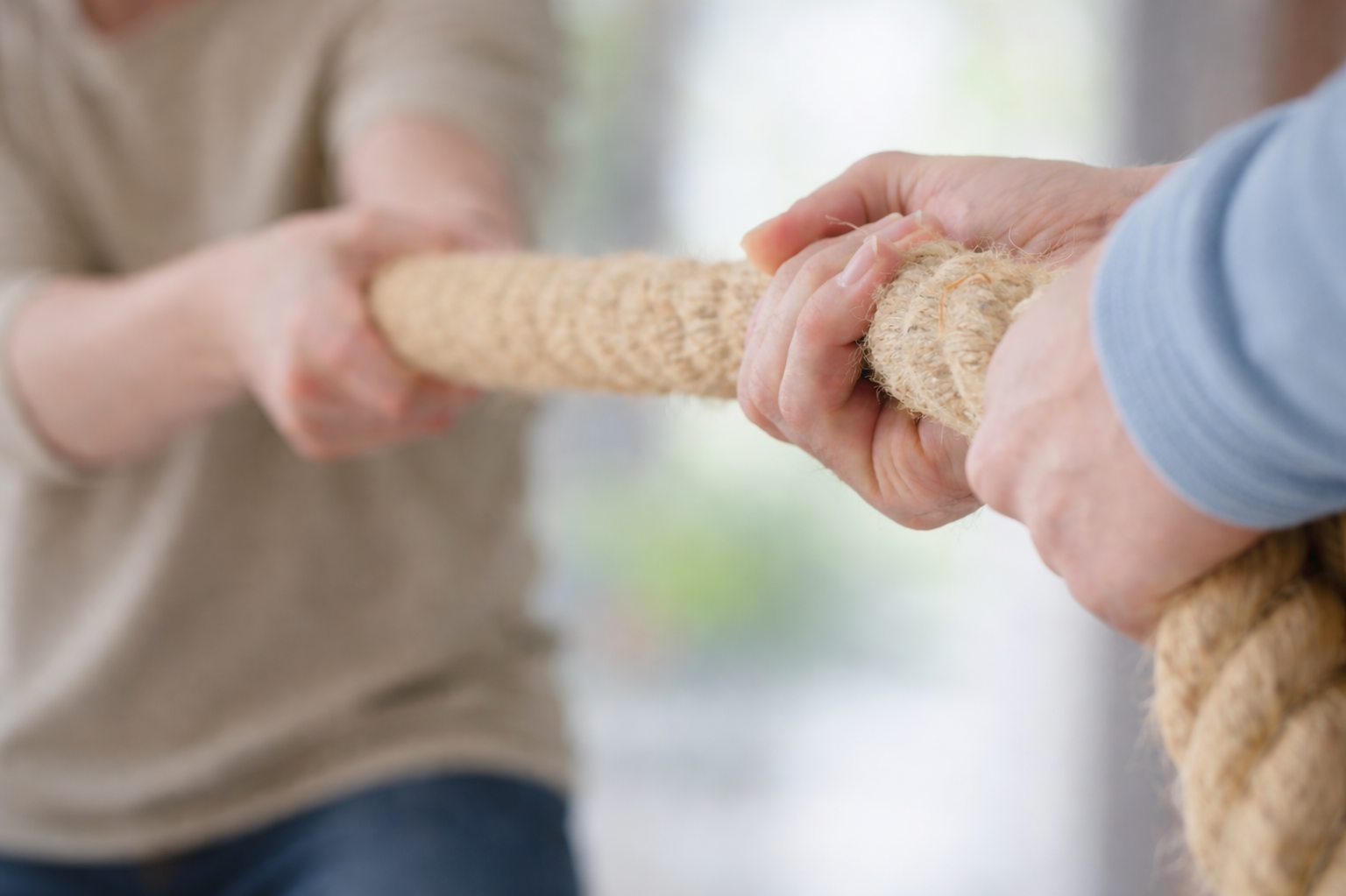 Zwei Personen ziehen an einem Seil als Sinnbild für einen festgefahrenen Konflikt