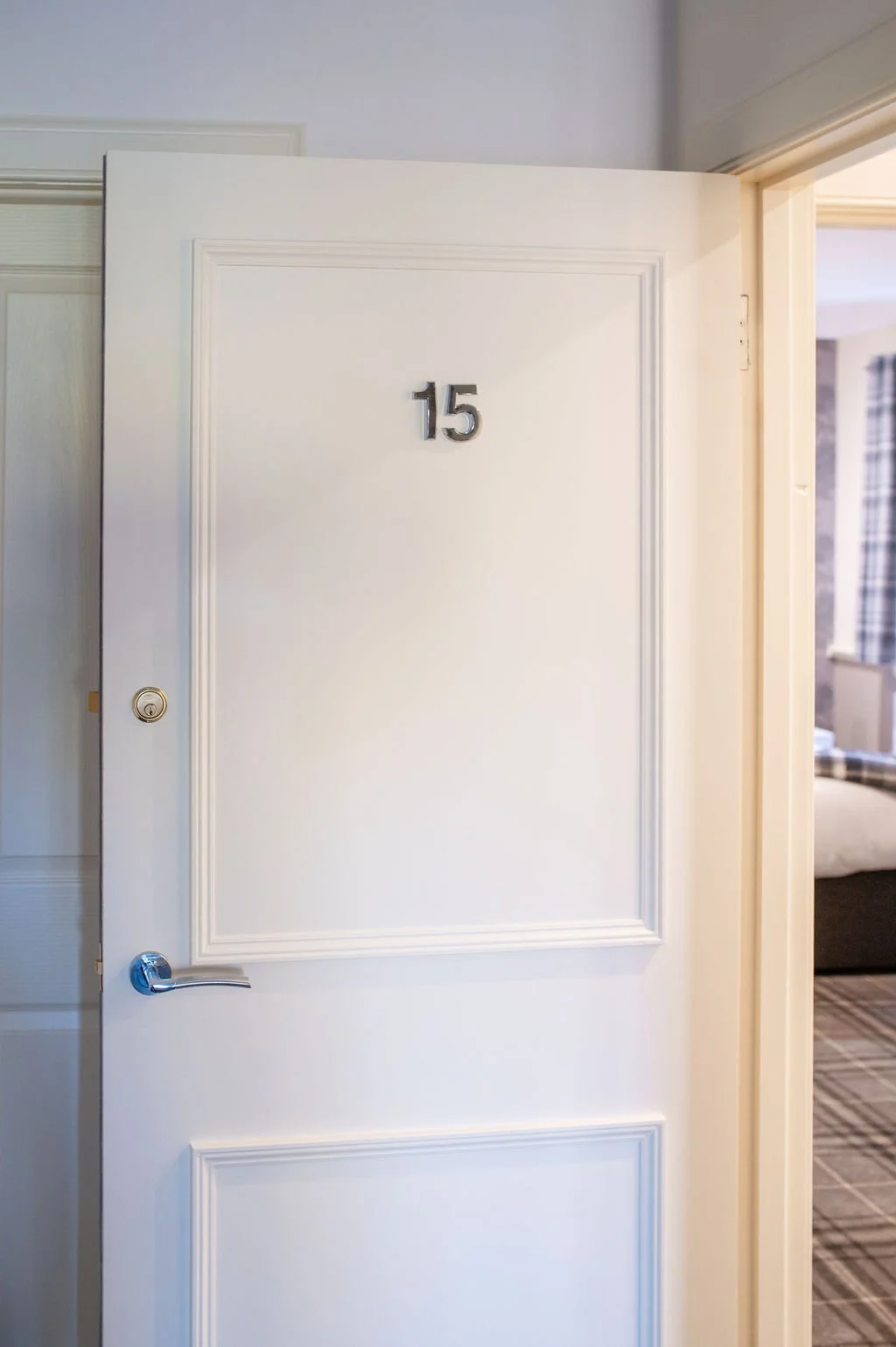 Hotel room door with the number 15 on it, slightly open to show part of the room inside.