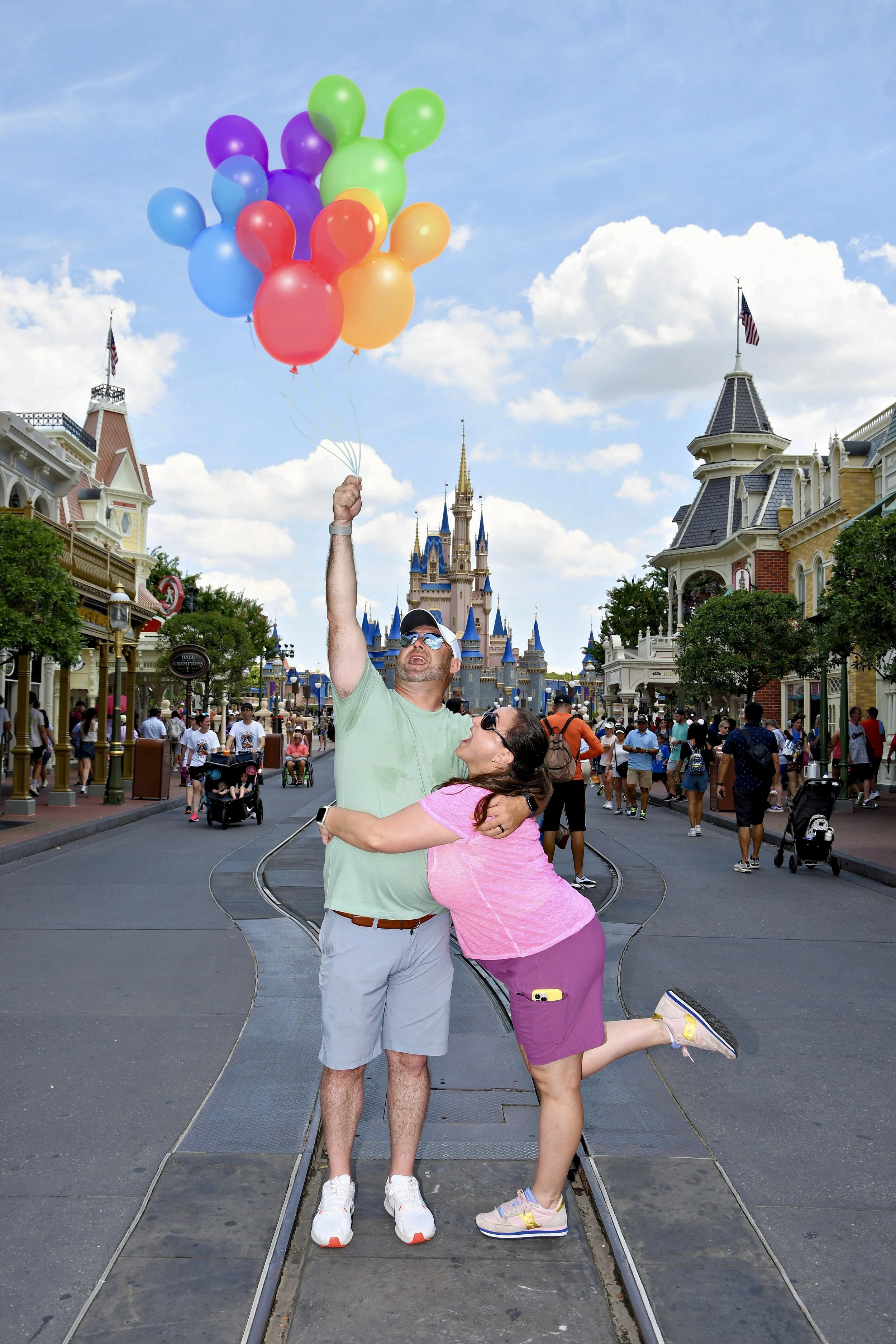 The Hartmans in front of the Cinderella Castle at Disney theme park, holding a bunch of colorful balloons.