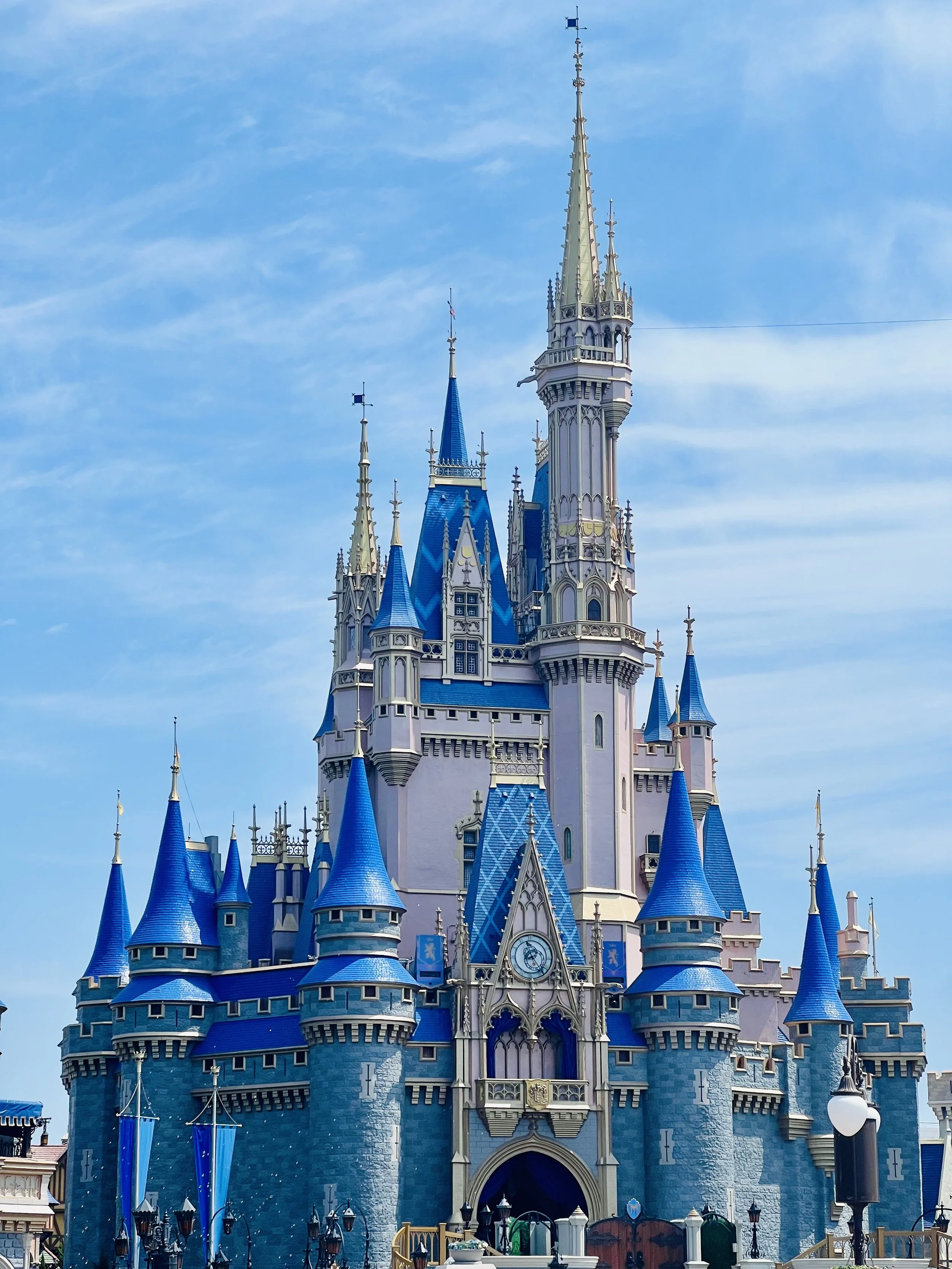 Disney castle with blue roofs and tall spires under a blue sky.