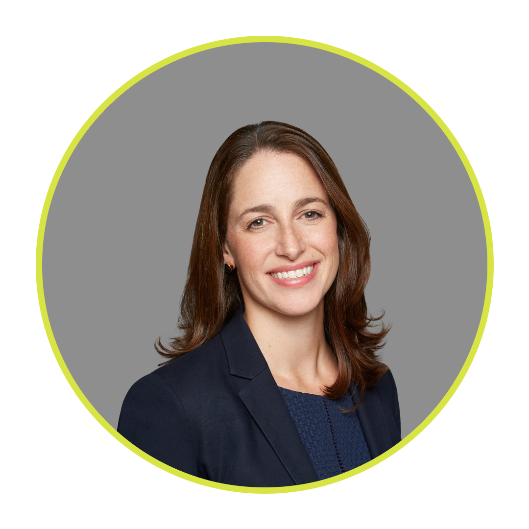 Professional woman with shoulder-length brown hair, smiling, wearing a navy blazer and a dark blue top, against a gray background with bright yellow circle overlay.