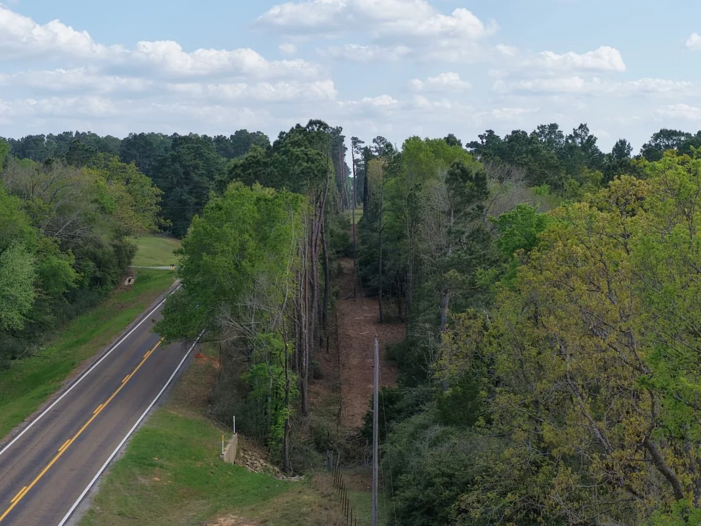 Wide aerial view of a utility corridor beside a road.