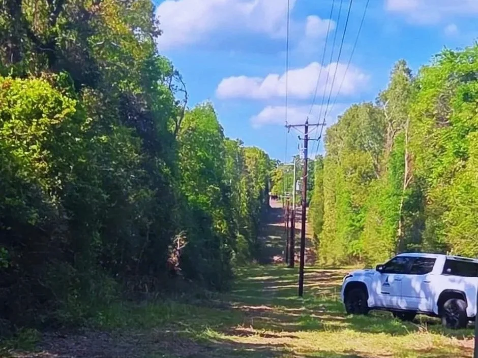 Pinnacle pickup truck beside a tree-lined utility corridor.