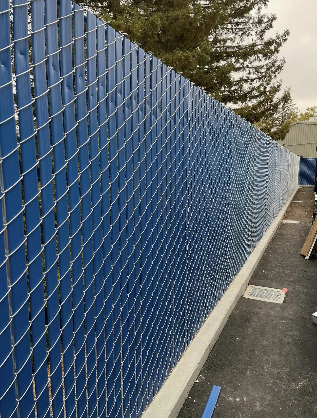 Blue Privacy slat chain link fence installed along commercial property perimeter