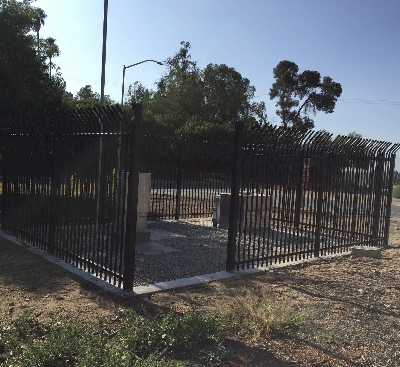 Commercial iron fence enclosure securing facility equipment and grounds