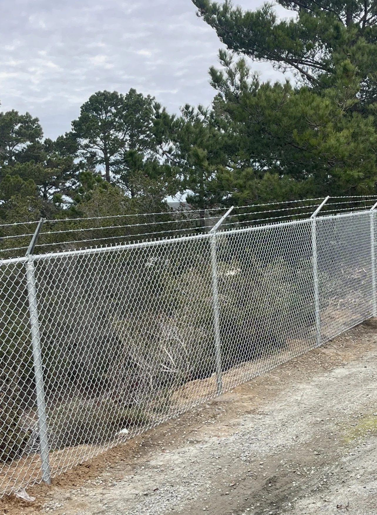 Commercial chain link security fence topped with barbed wire deterrent