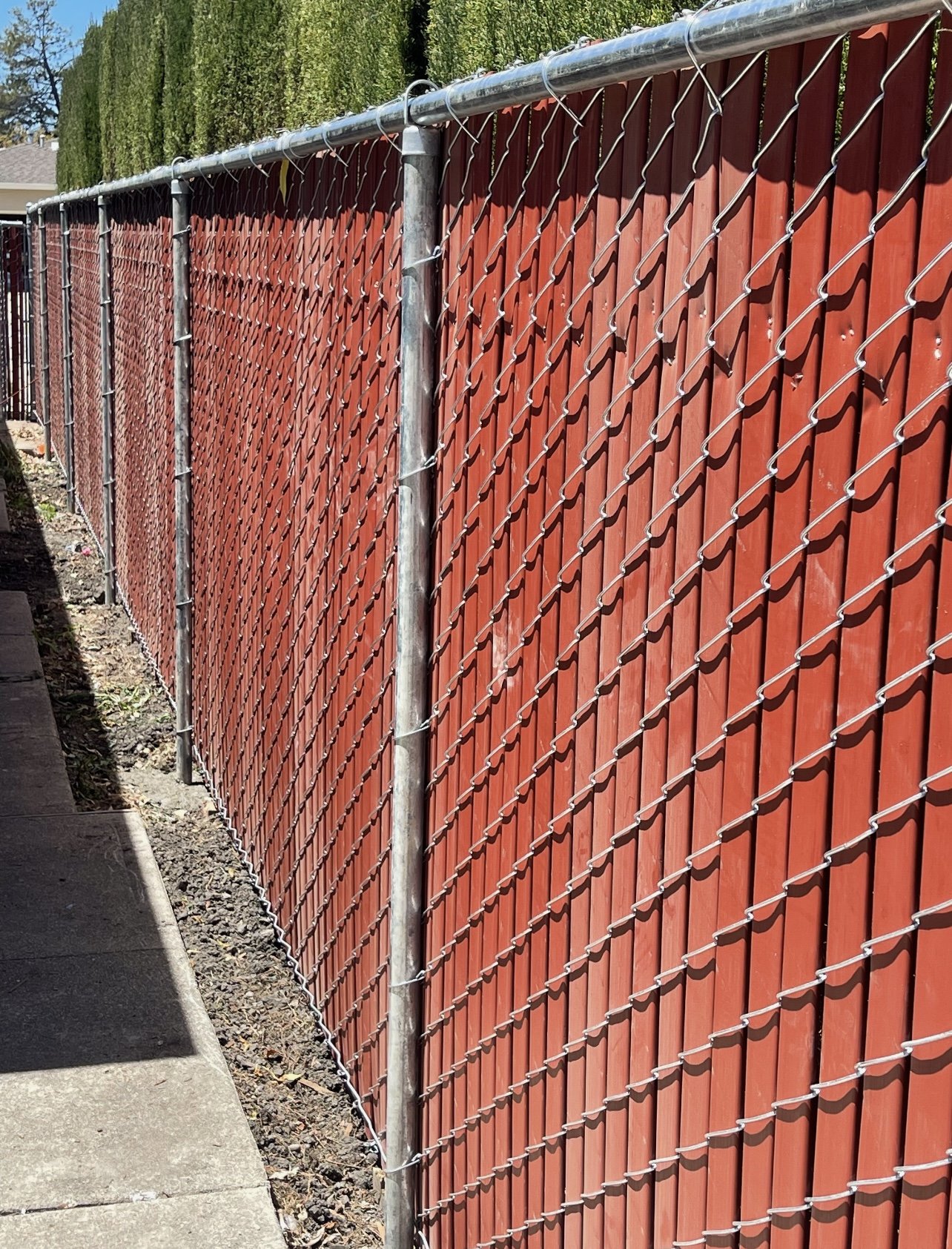 Red privacy slat chain link fence installed along commercial property perimeter