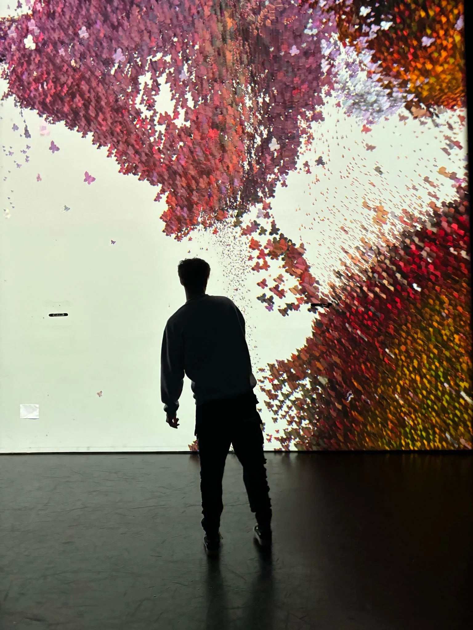 Silhouette eines Mannes vor einer großen, bunten, pixelartigen Kunstinstallation, die wie ein Baum aussieht.
