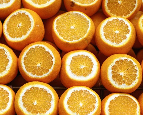 Multiple halved oranges with visible juice-filled insides.