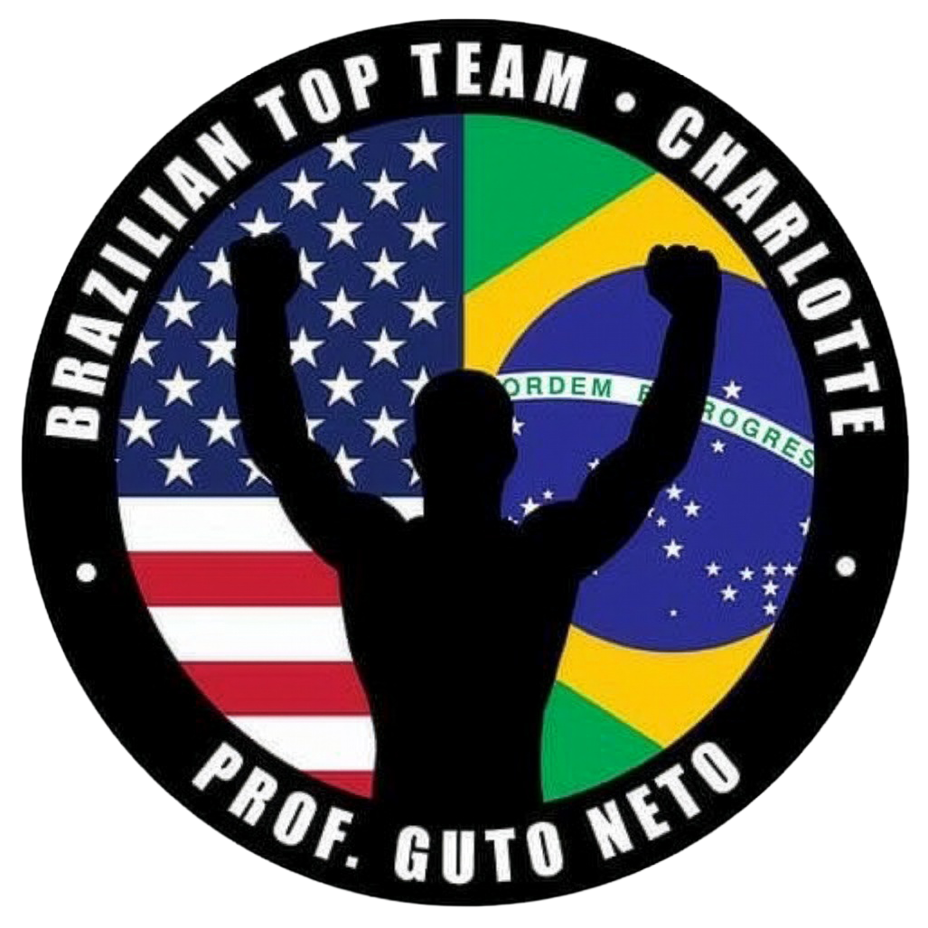 A circular emblem featuring a silhouette of a man with raised fists, set against the flags of the United States and Brazil. The outer ring has text reading "Brazilian Top Team - Charlotte" and "Prof. Guto Neto."