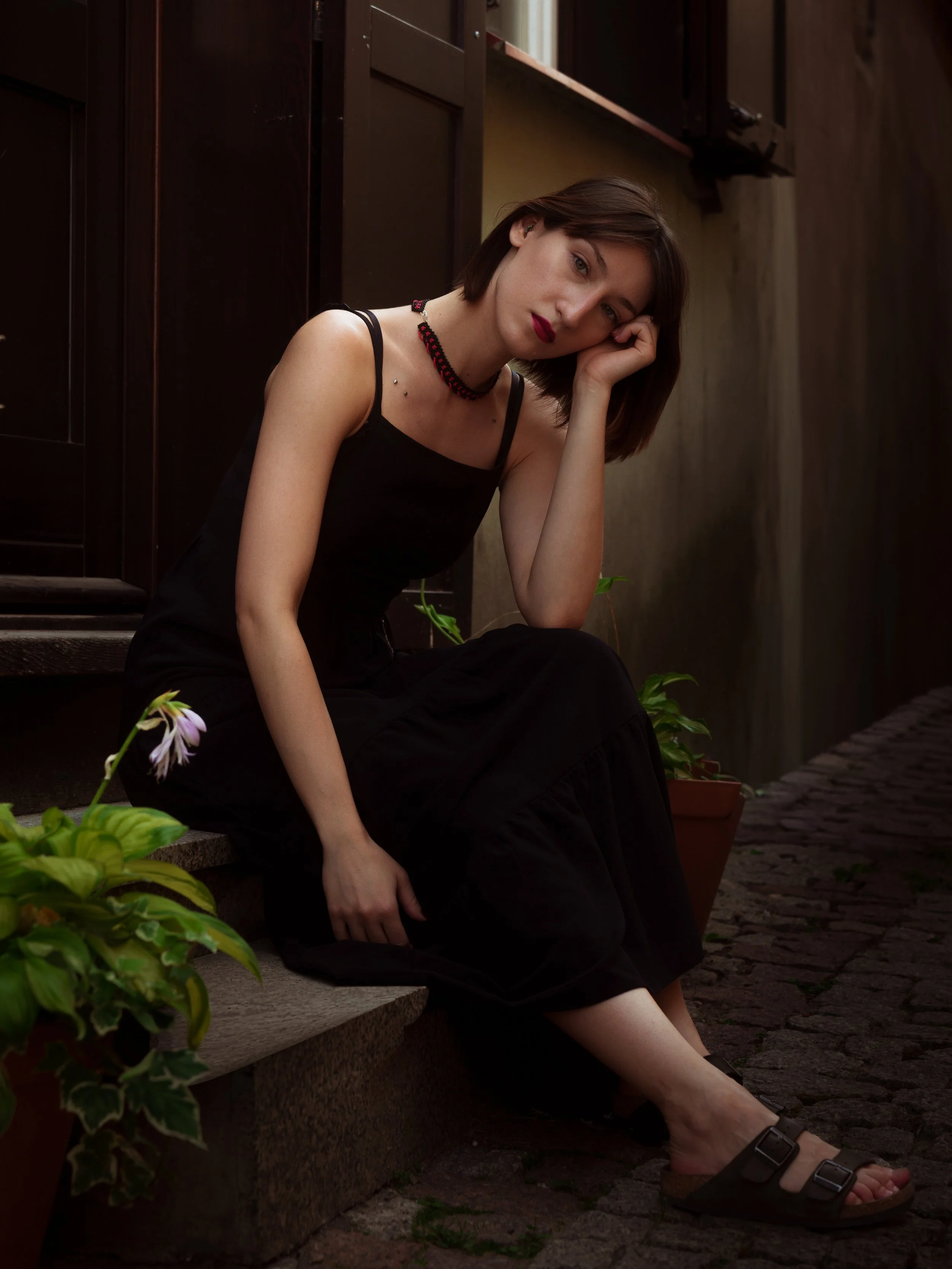 Portret kobiety w czarnej sukience siedzącej przy wejściu do budynku w Lublinie