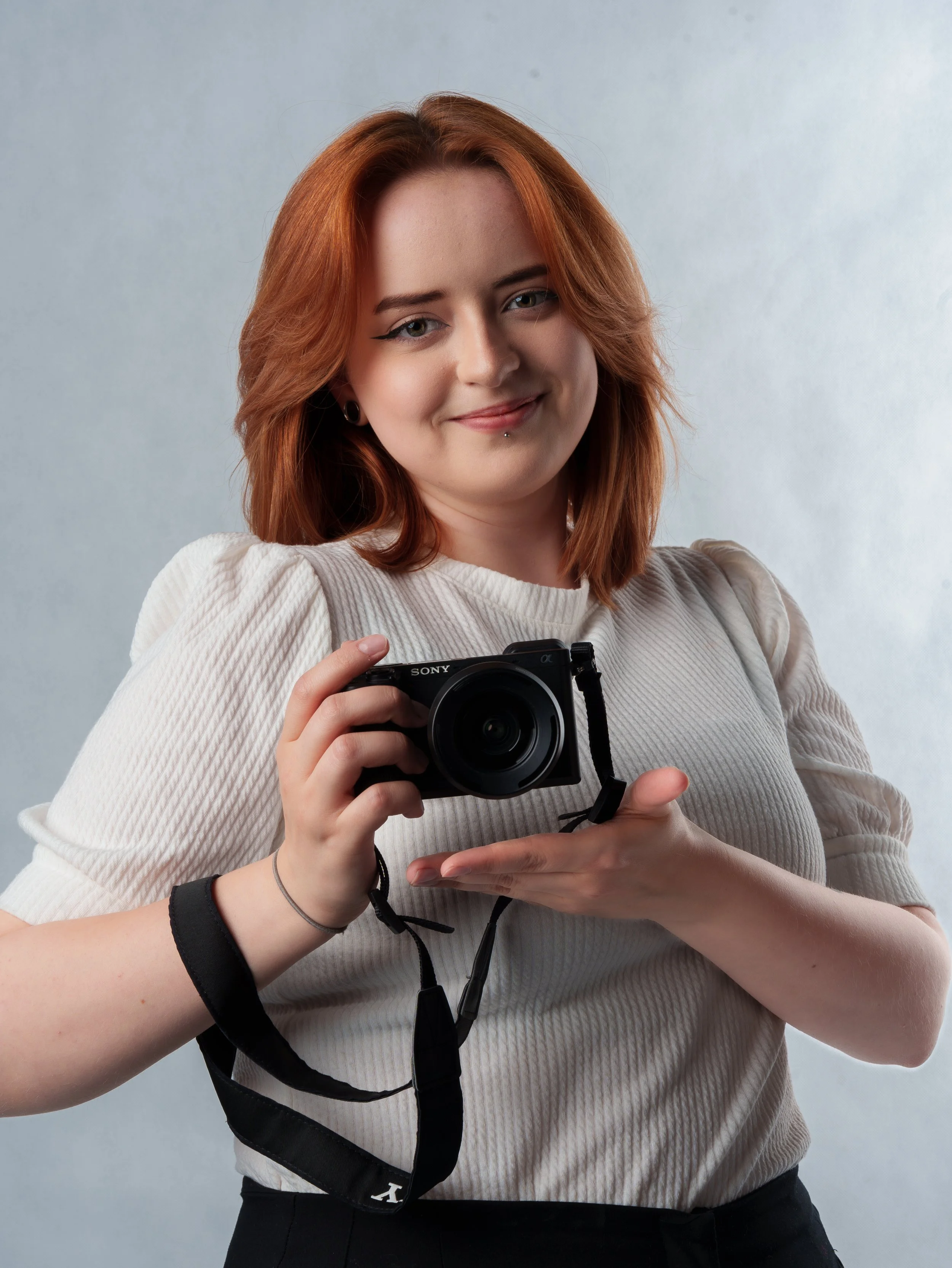 Portret rudowłosej kobiety trzymającej aparat fotograficzny