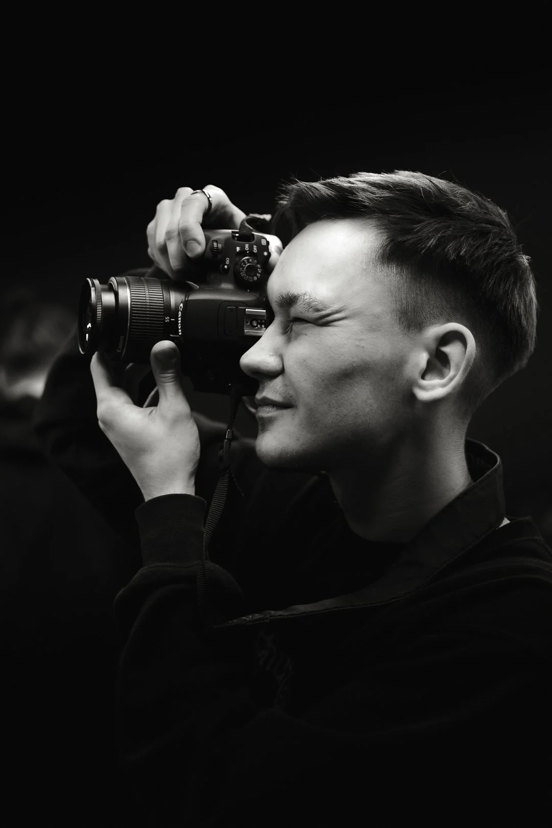 Czarno-biały portret mężczyzny fotografującego aparatem