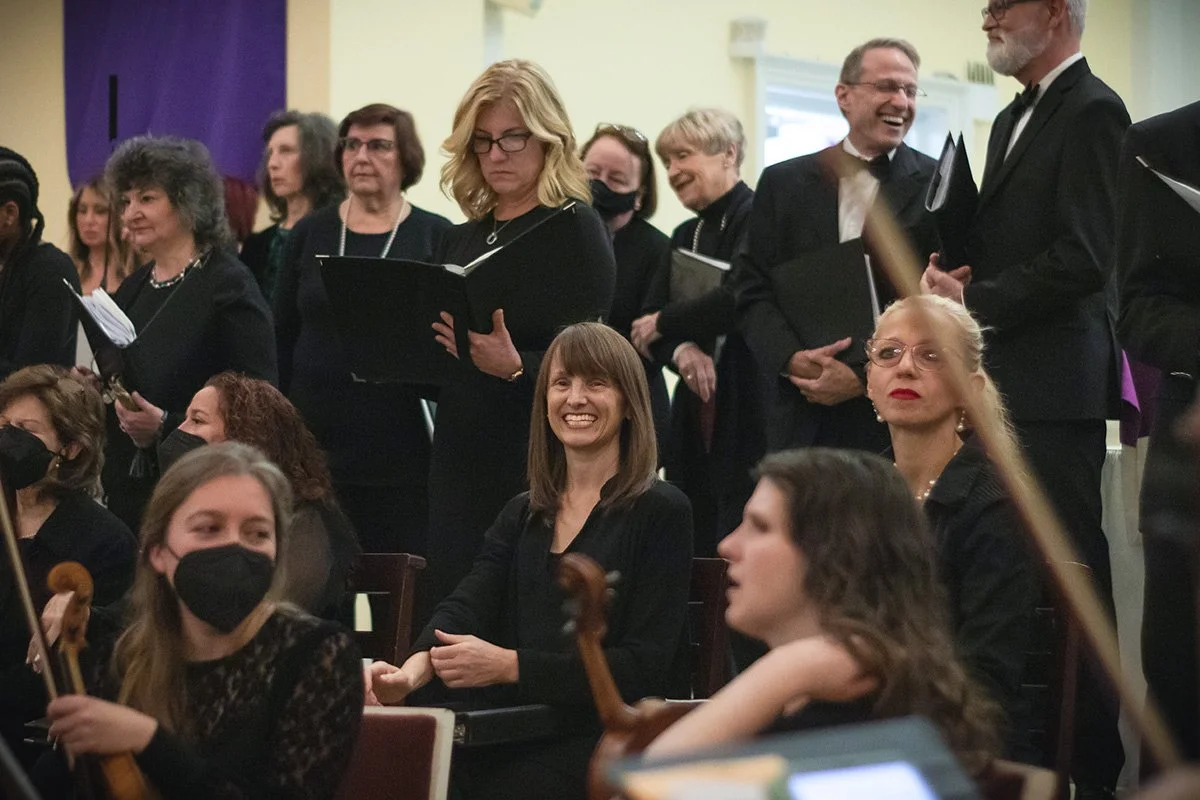 A candid image of members of the Richmond Choral Society smiling during a concert.