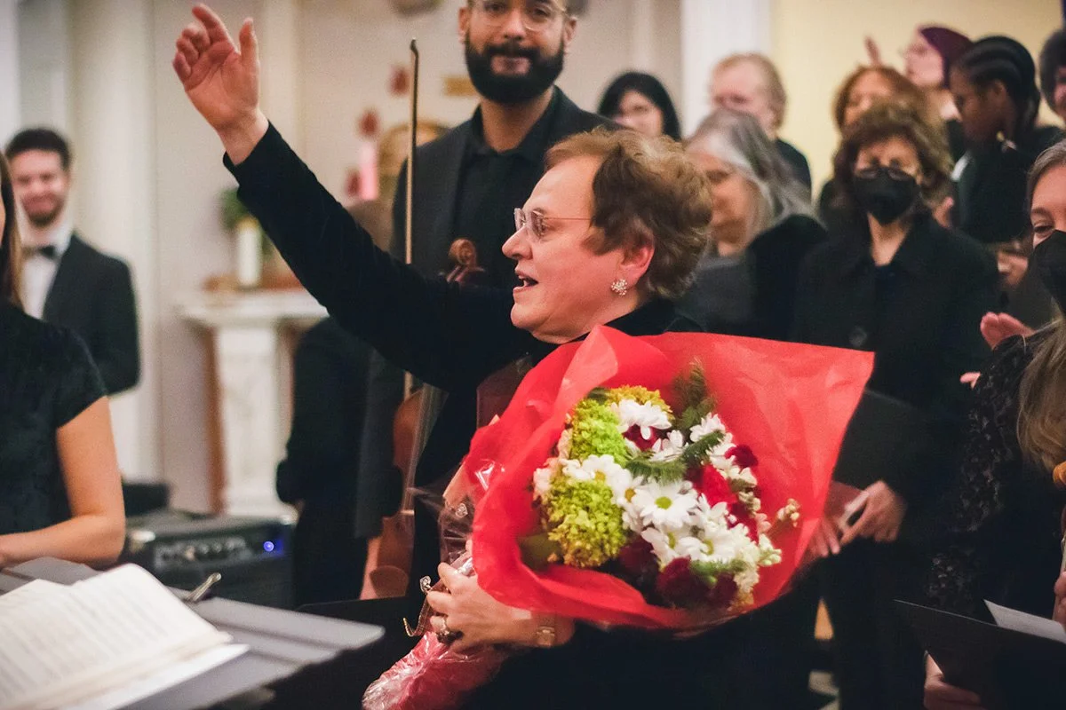 Music Director Marina Alexander holding a bouquet of flowers at a Richmond Choral Society concert.