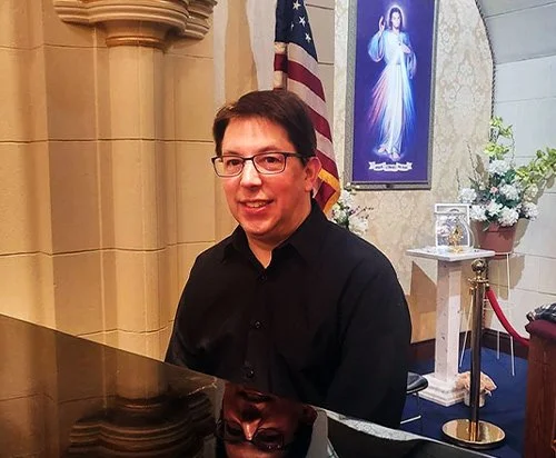 Thomas Molessa sits at a piano, smiling