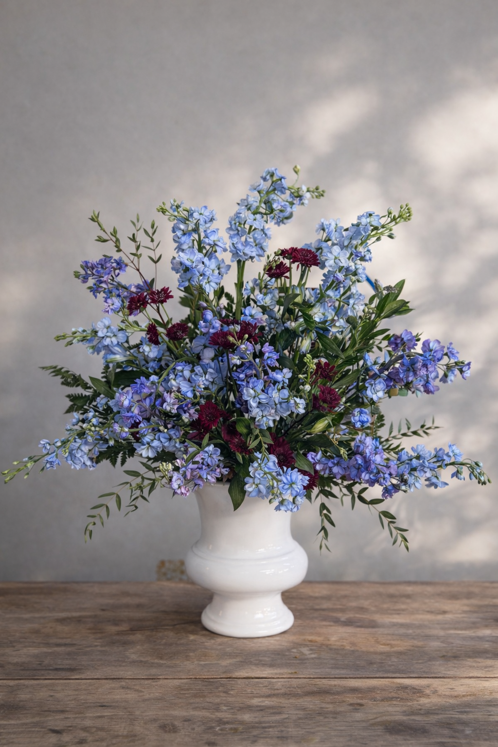 A bouquet of blue, purple, and red flowers in a white vase St. George delivery.