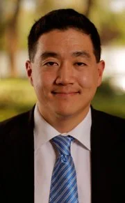 Portrait of a man in a suit and tie outdoors with greenery in the background