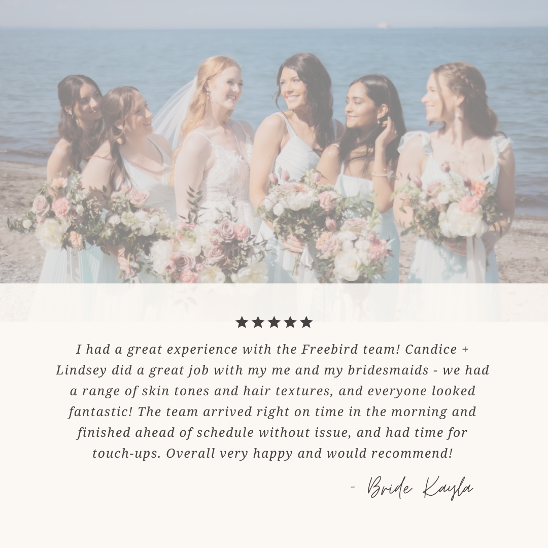 A group of six women, including a bride, at the beach holding bouquets of flowers. They are smiling and dressed in light-colored dresses, with the ocean in the background.