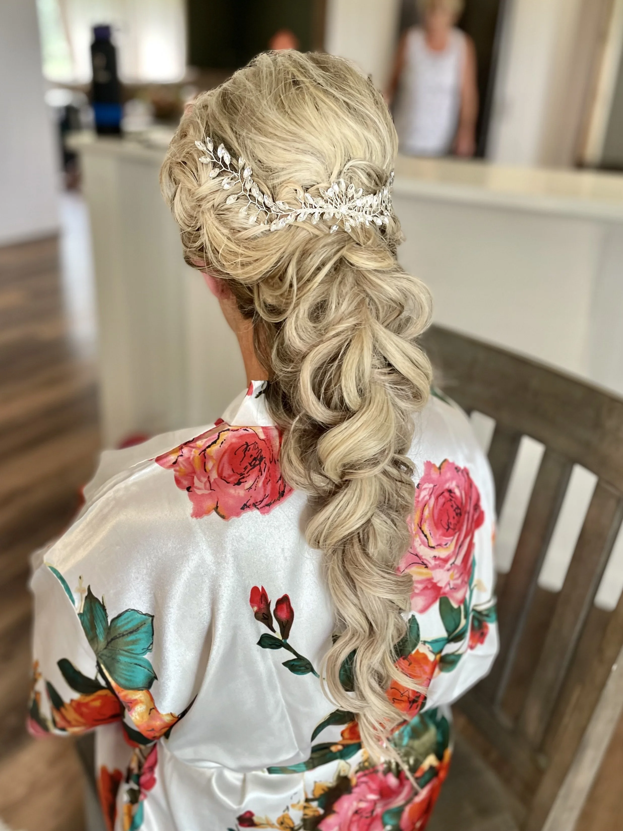 Woman with intricate braided hairstyle and hair accessory, wearing floral robe.