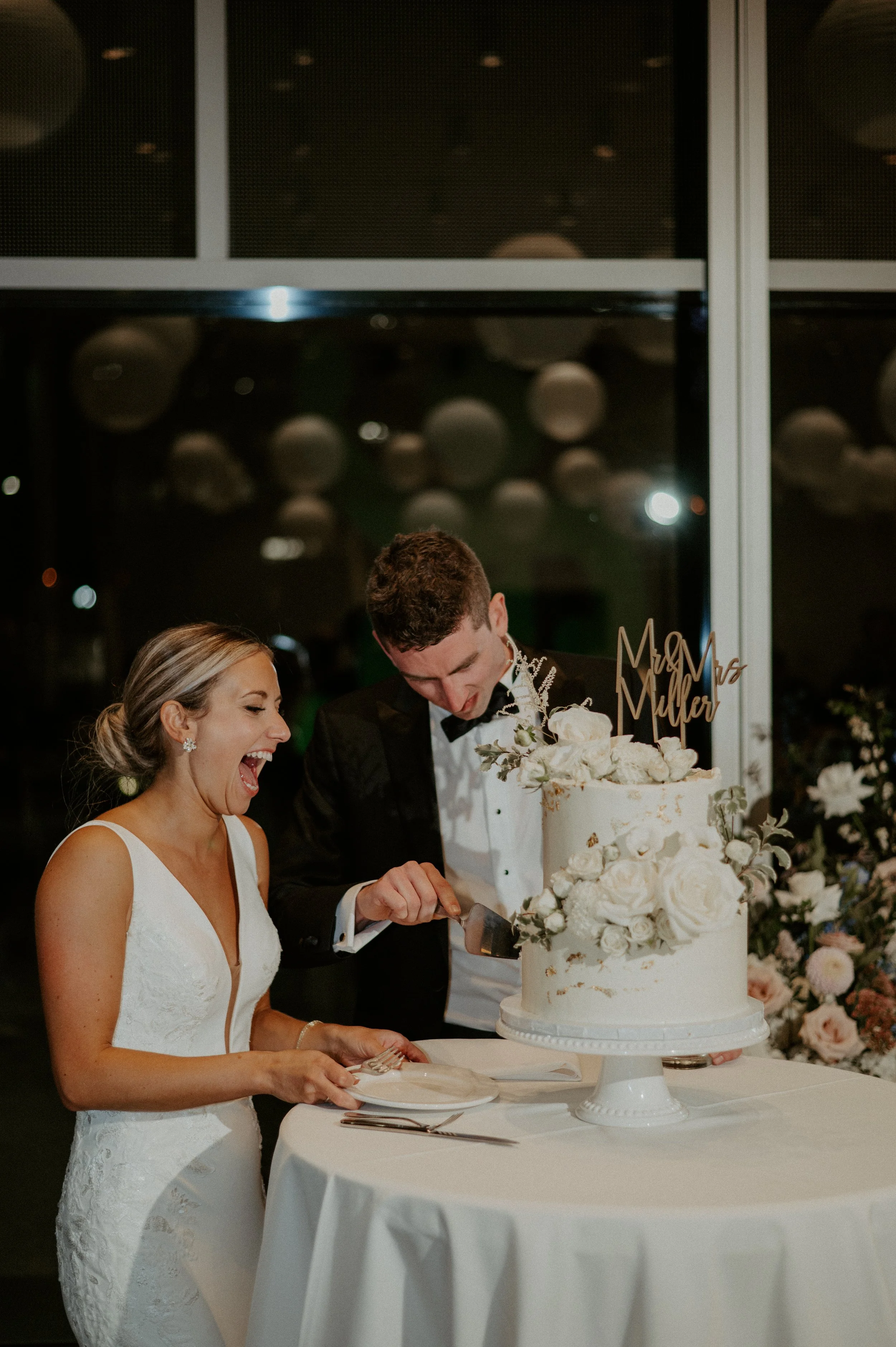 Bride and groom cutting a wedding cake with floral decorations.