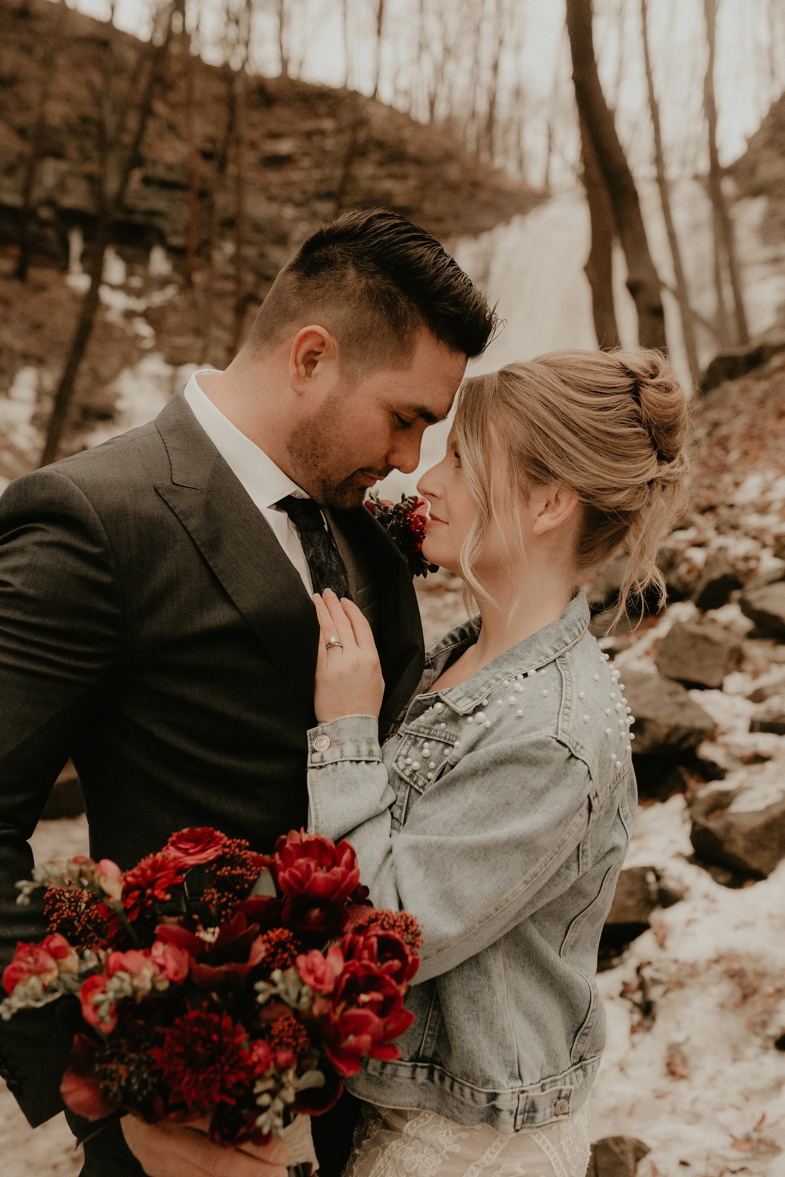 Couple embracing with red flowers in snowy outdoor setting.