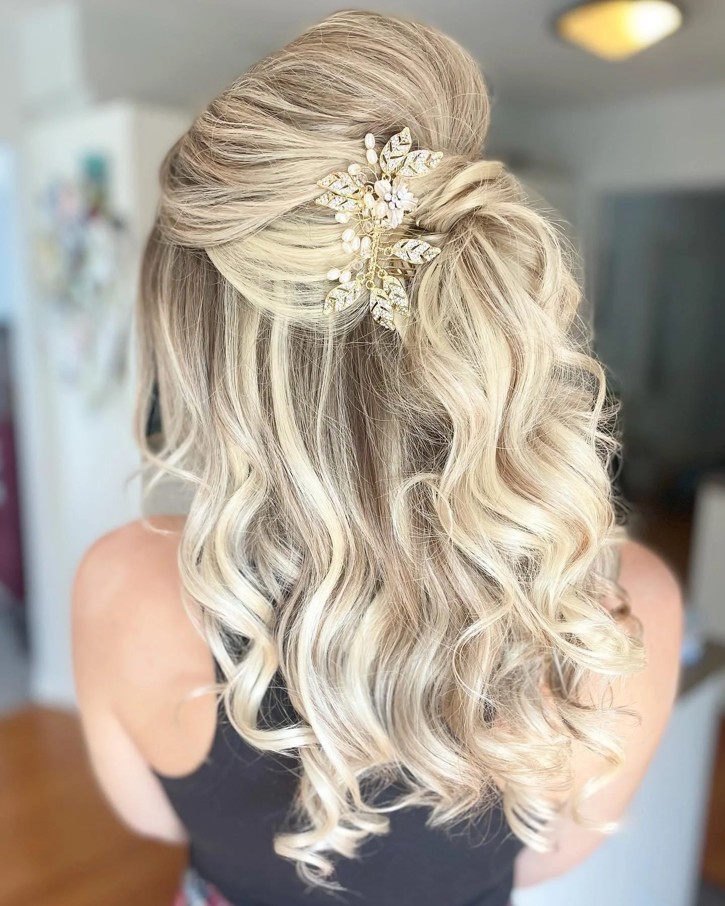 Woman with curly blonde hair styled with floral hair accessory.