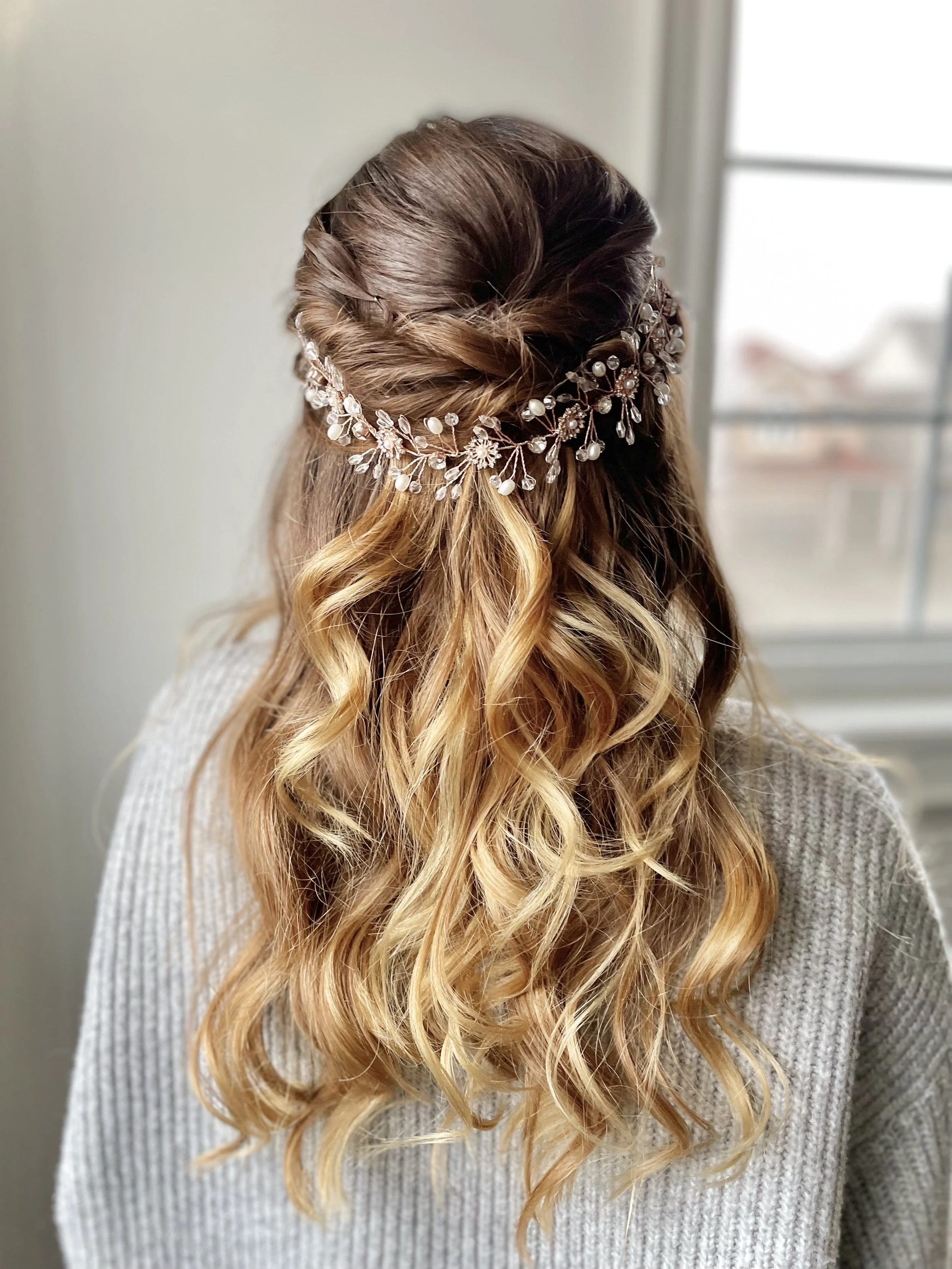Back view of a woman's styled hair with curls and a decorative hairpiece.
