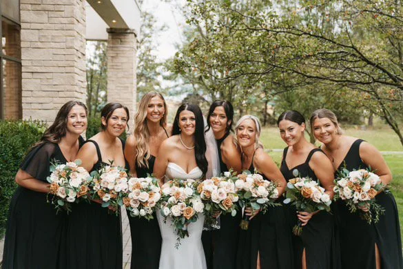 Bridal party with bridesmaids in black dresses holding bouquets