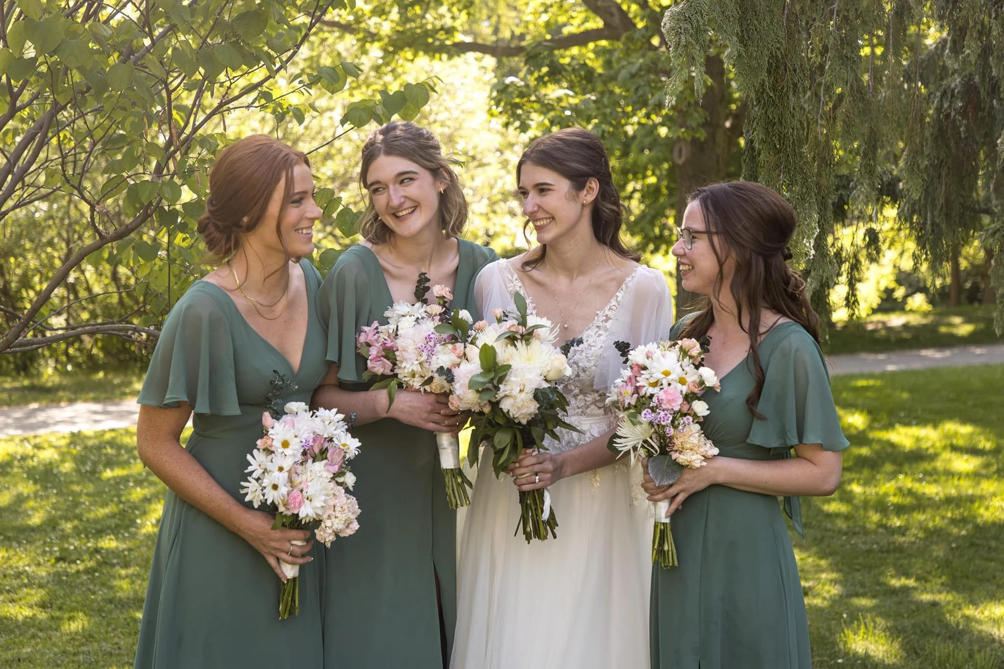 Bride with bridesmaids holding bouquets in a garden setting.