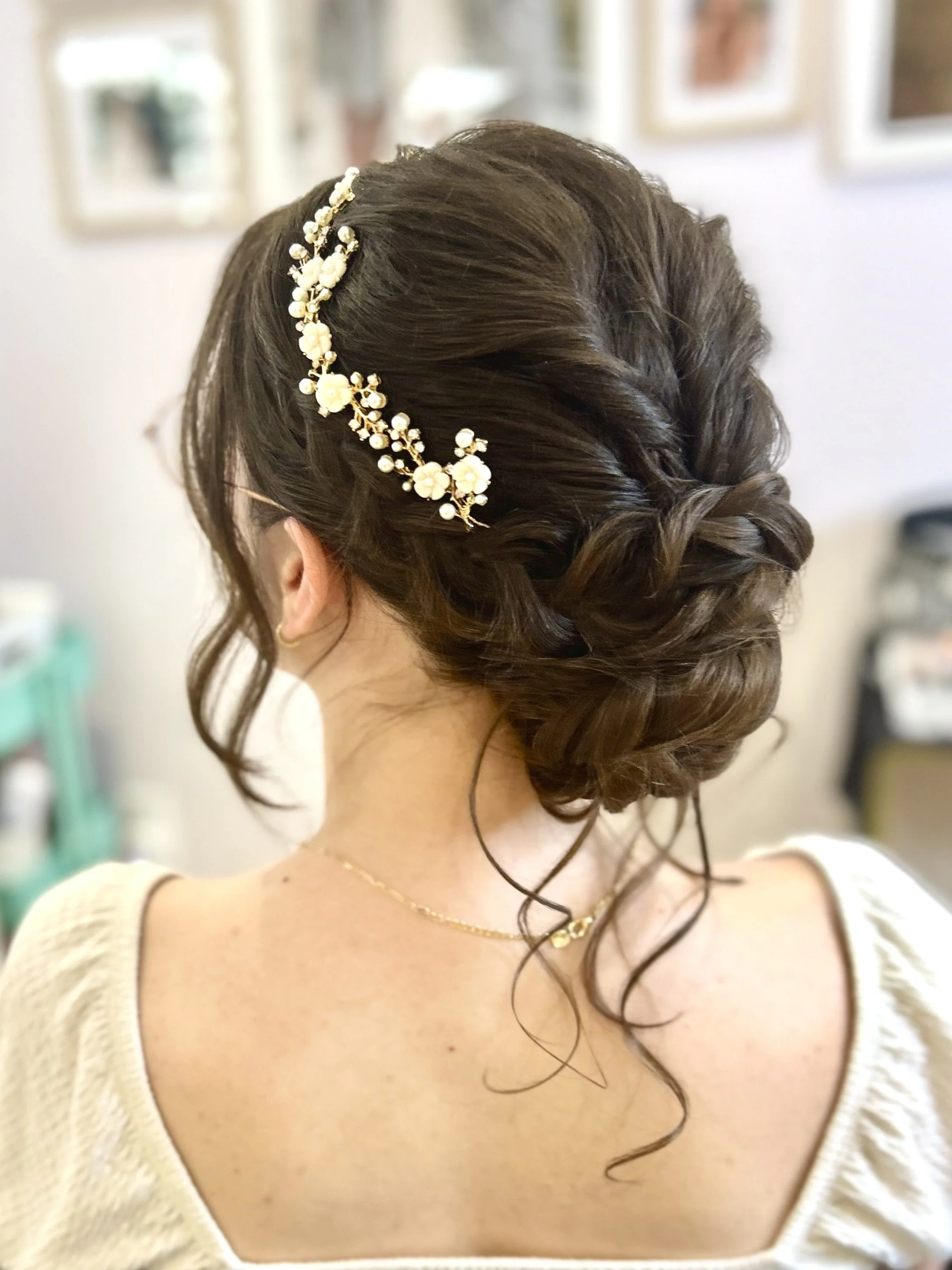 Woman with braided updo adorned with floral hair accessory.