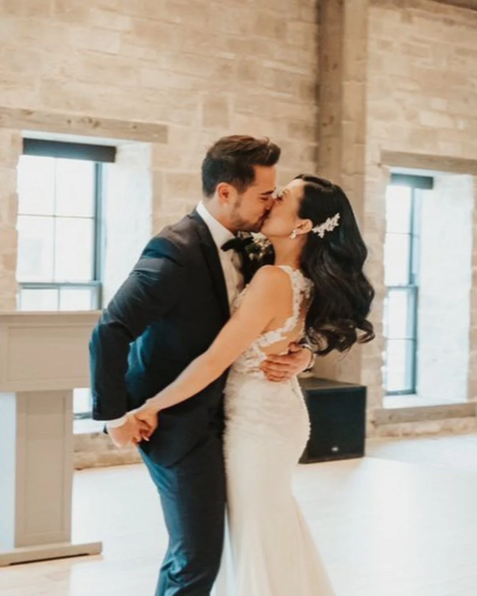 Bride and groom kissing indoors during a wedding ceremony.