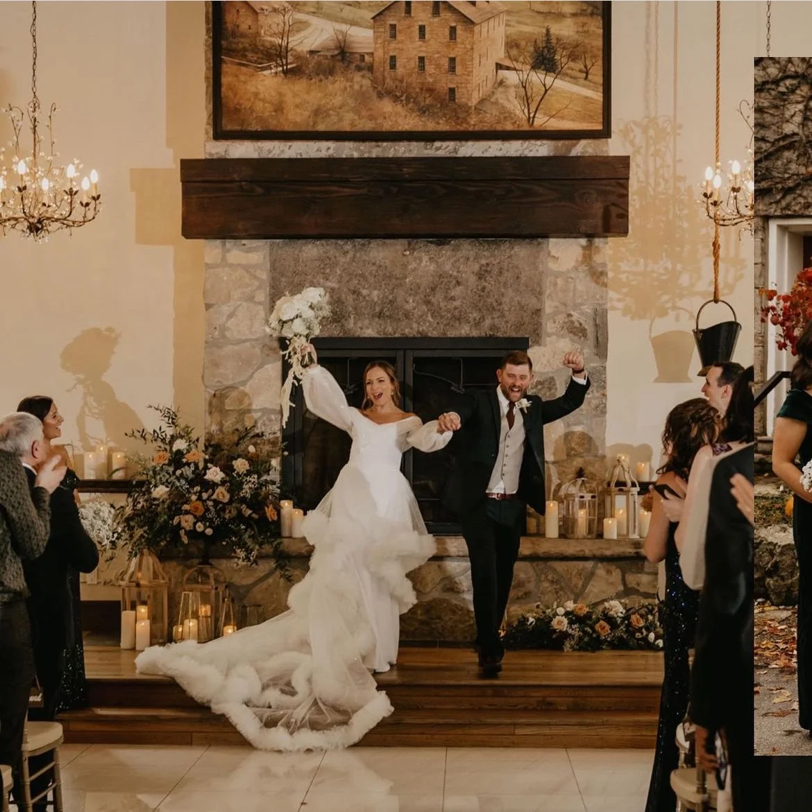 A bride and groom celebrating inside a decorated venue, with onlookers clapping. The bride is wearing a white dress and holding a bouquet, while the groom is in a suit. The background features a stone fireplace, candles, flowers, and a large painting
