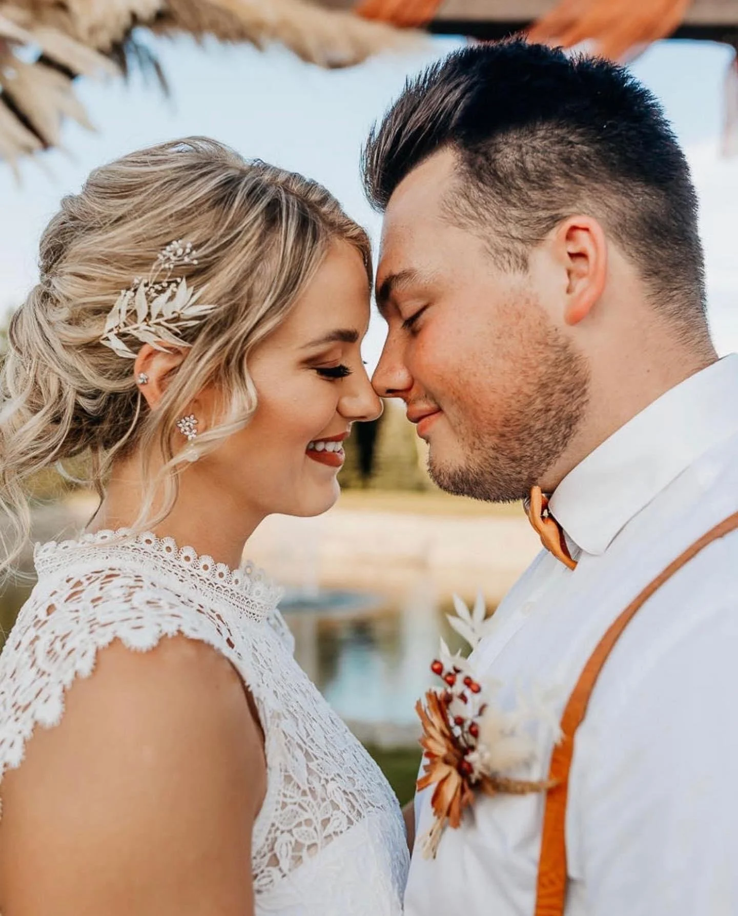 Bride and groom touching foreheads in wedding attire.