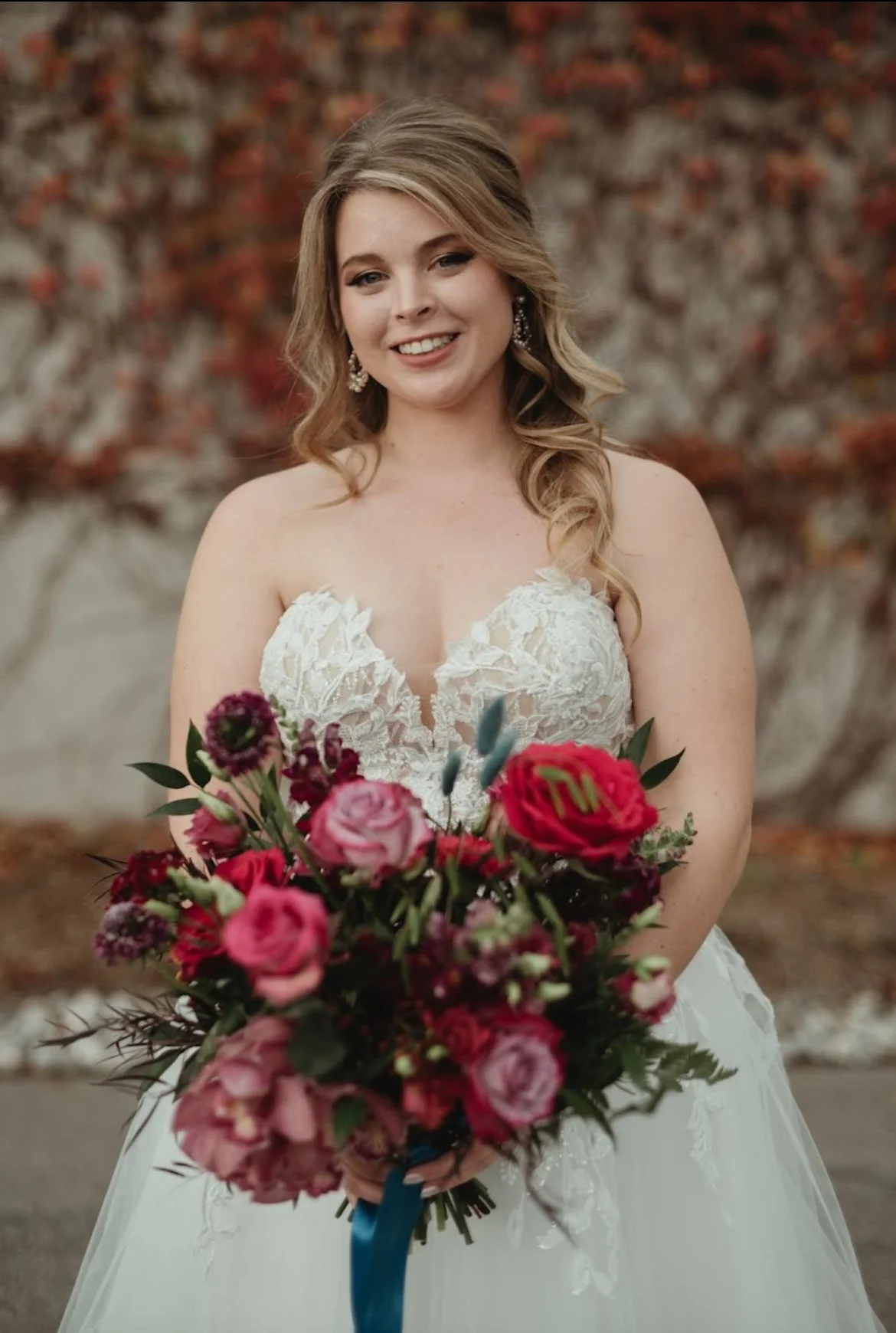 Bride holding a colorful bouquet in front of a blurred background.