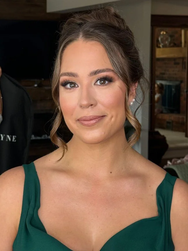 Woman with brown hair wearing a dark green dress, smiling indoors.