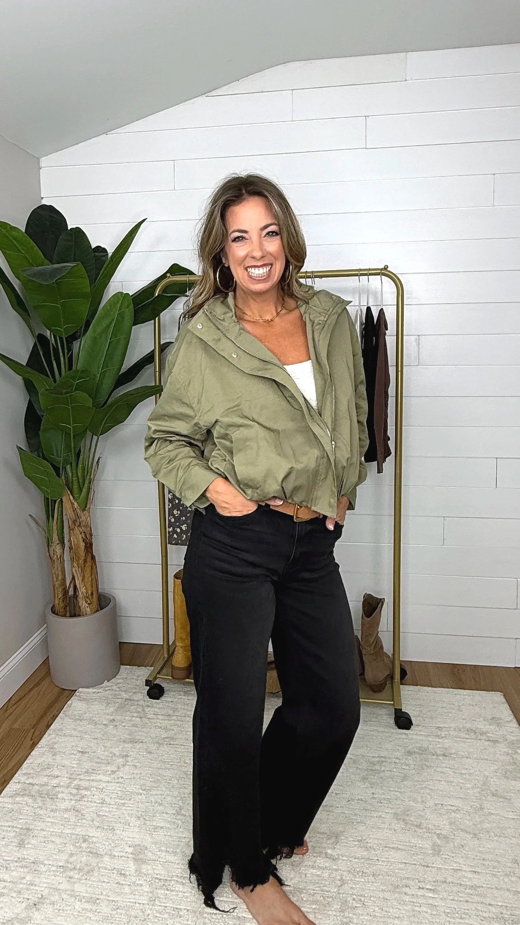 Olive zip up mock neck cropped jacket worn open over white tank and black wide leg pants with gold belt