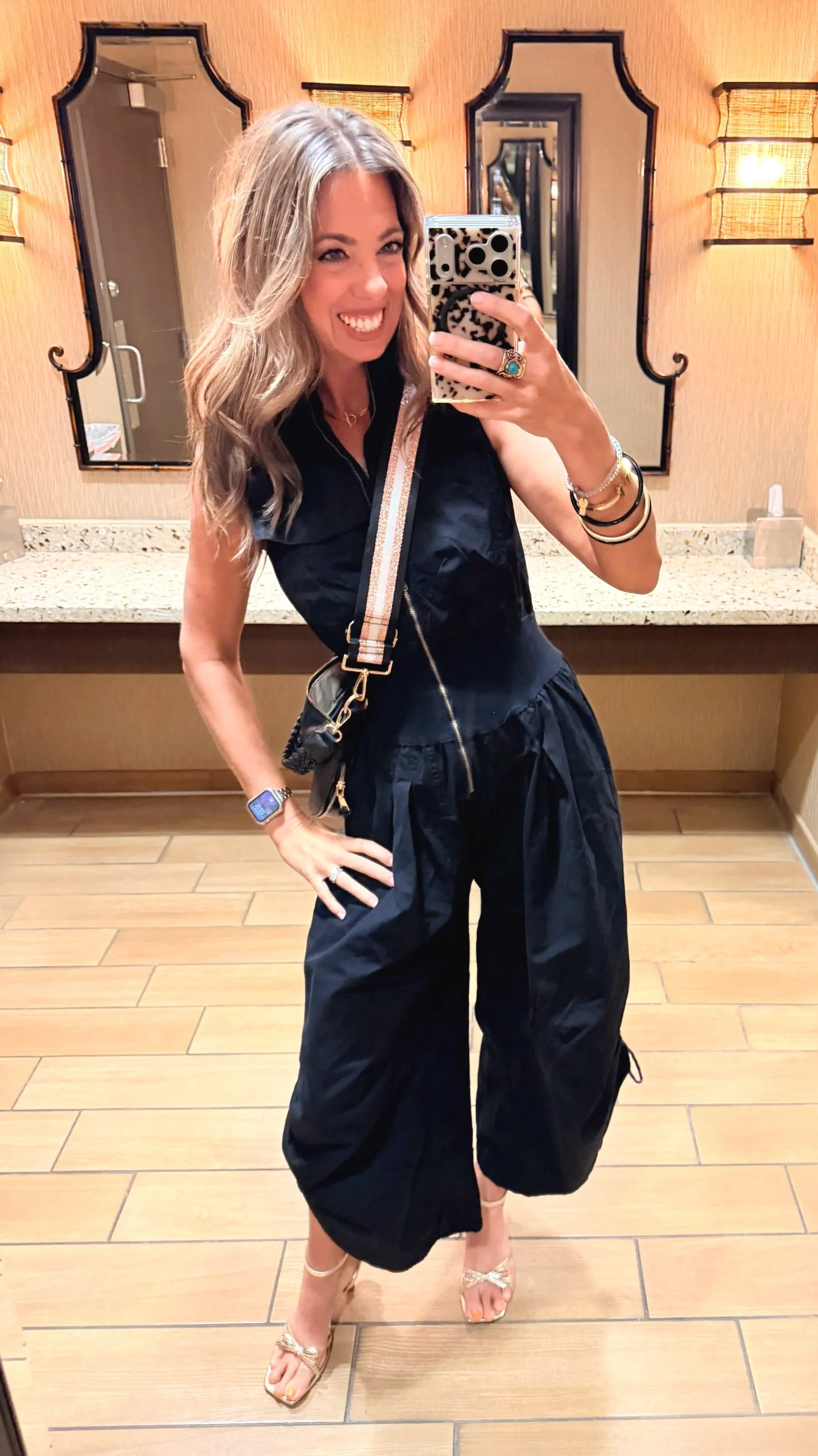 Black mineral washed zip front jumpsuit with balloon legs styled with gold heeled sandals