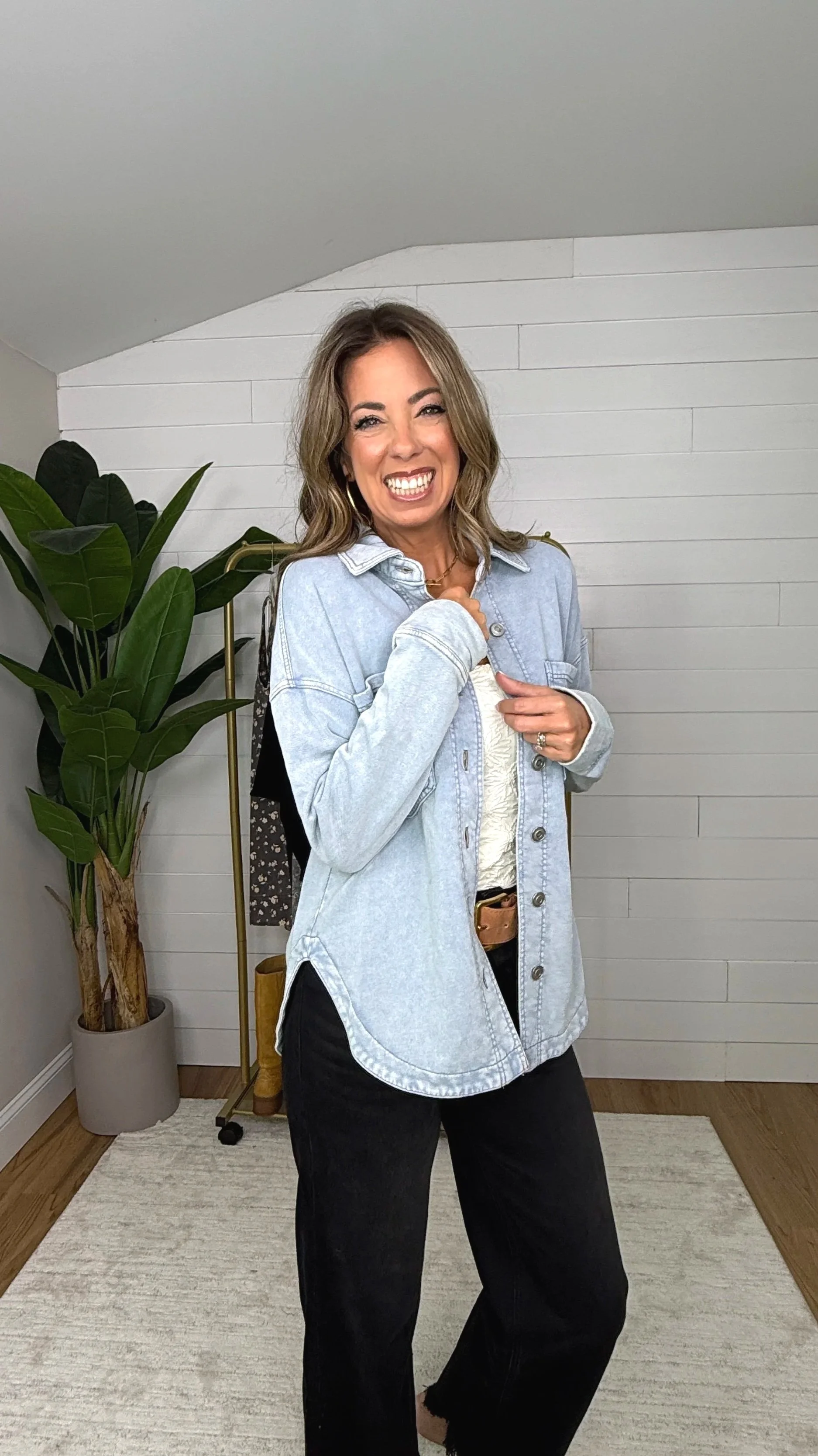 Full length view of acid wash blue button down shacket with curved hem styled with black wide leg jeans