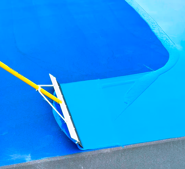 Close-up of a roller at the edge of a blue swimming pool, being used for maintenance or cleaning.