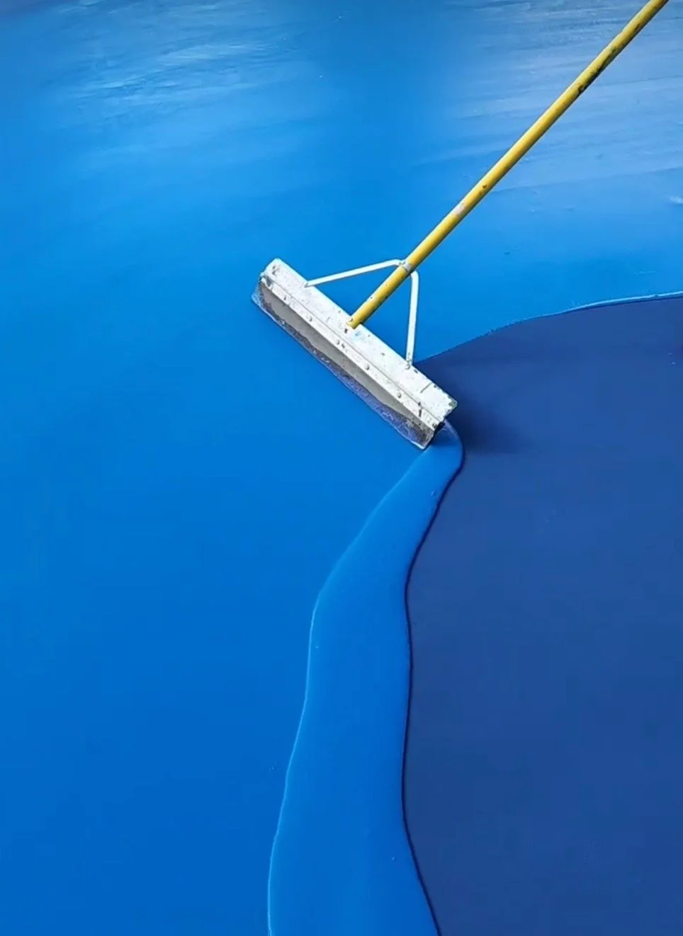 A pool skimmer cleaning the surface of a blue swimming pool.