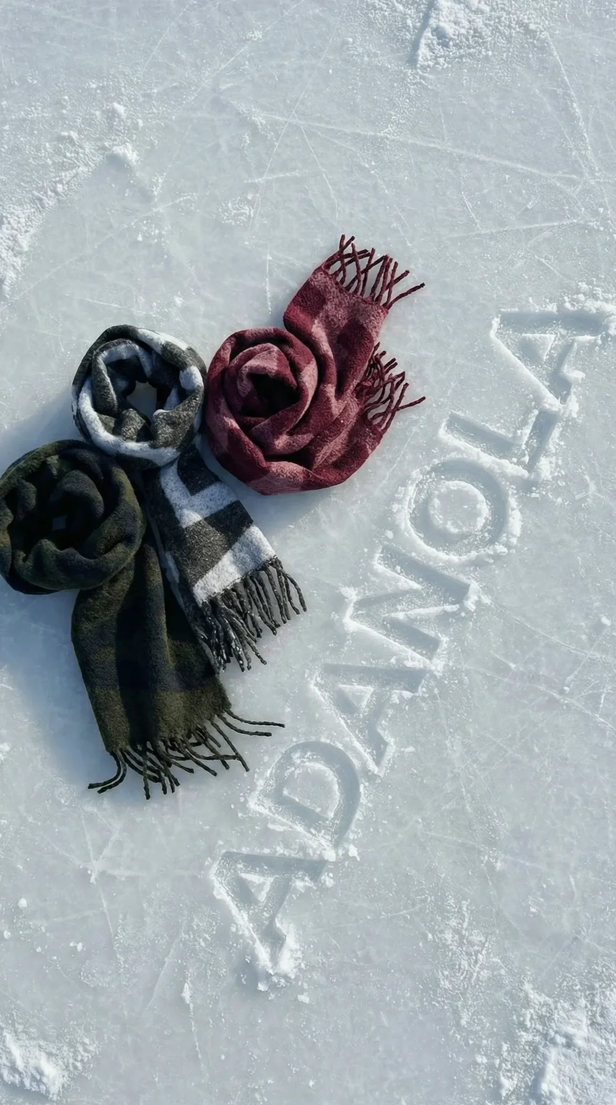 Two scarves and a glove placed on the ice with the phrase "DAY OFF" written in the snow.