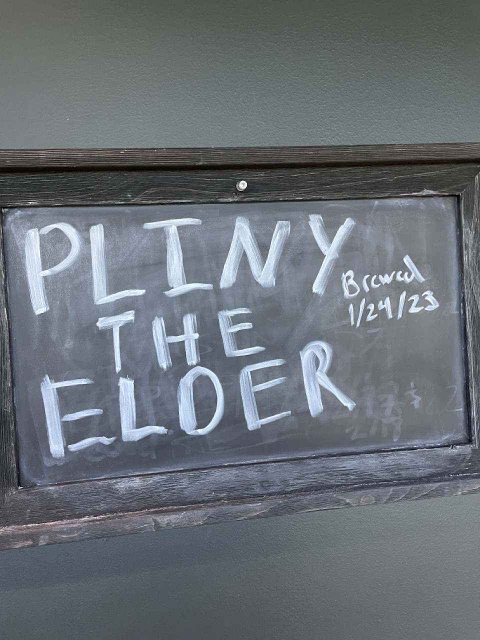 A chalkboard sign with the words 'PLINY THE ELDER' written on it, along with the date '1/24/23' and the word 'Brewed' written in smaller letters.