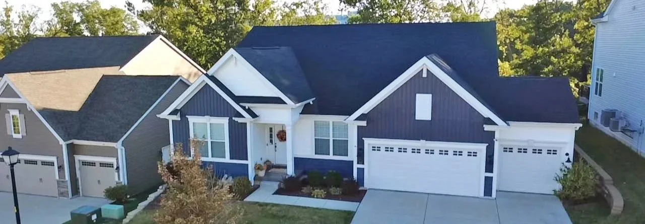 A modern house with a blue and white exterior and new siding by National Roofing to protect home from St. Louis storm weather and damage