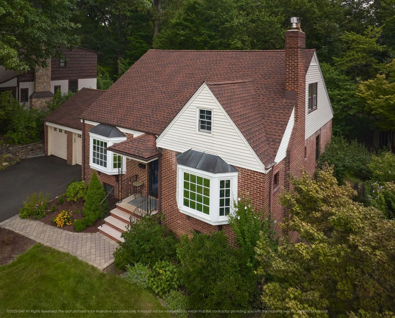 An aerial view of a two-story brick house with a gabled roof covered in red shingles, white siding by National Roofing St. Louis to protect your home from storm damage, bad weather, roof replacements and leaks.
