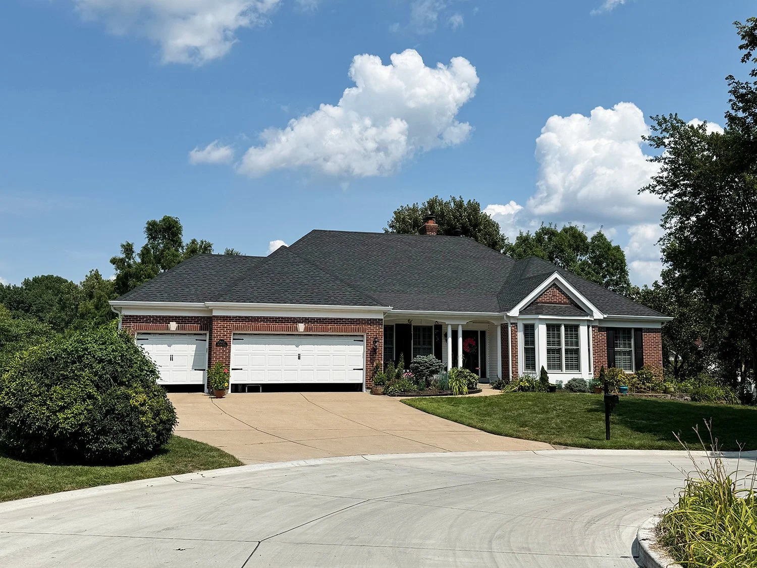 A single-story brick house with new shingles and gutters by National Roofing St. Louis after storm damage.